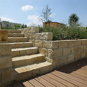 Eine individuelle Treppe aus Sandsteinblöcken führt in die zweite Gartenebene
